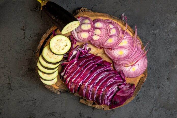 recettes-pour-tous_Recettes d’oignons inconnues, redécouvrez ce légume comme jamais_top-view-sliced-vegetables-red-onion-cabbage-eggplant-wooden-board-black oignon